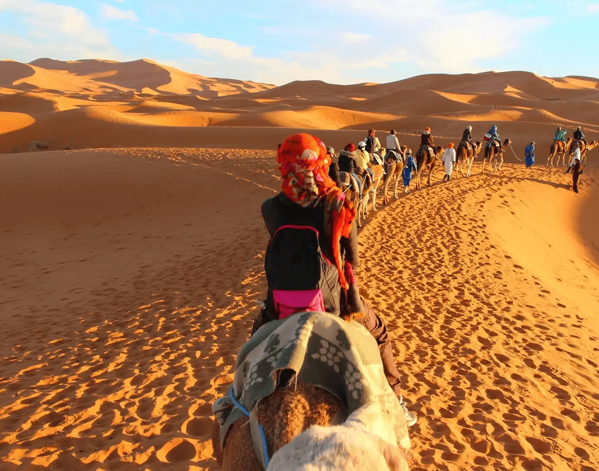 a group riding camels in the Moroccan desert
